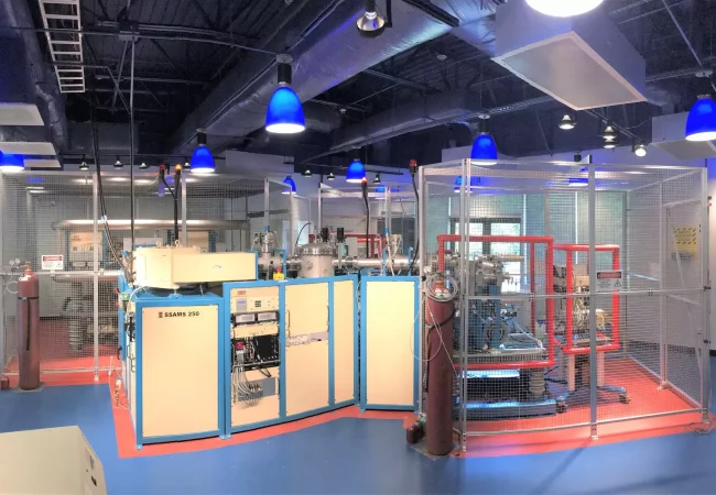 A high-tech laboratory featuring a SSAMS50 accelerator mass spectrometer surrounded by equipment and safety cages, used for precise isotope analysis.