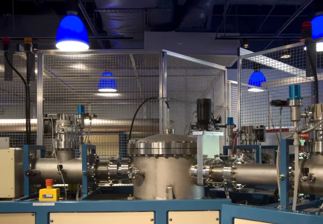 Close-up of an accelerator mass spectrometer in a laboratory setting, featuring intricate machinery and secure enclosures for isotope analysis.