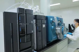 A scientist operates advanced analytical instruments, including an LC-MS system, for analytical development and quality control in a laboratory setting.