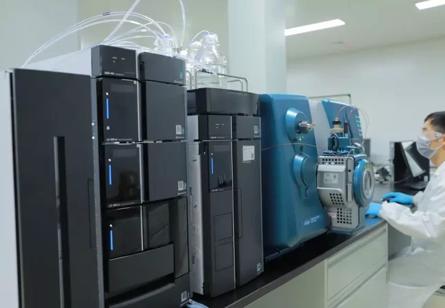 A scientist operates advanced analytical instruments, including an LC-MS system, for analytical development and quality control in a laboratory setting.