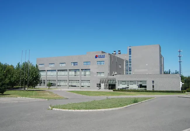 A modern multi-story building with large glass windows, located in Beijing, surrounded by greenery under a clear blue sky.