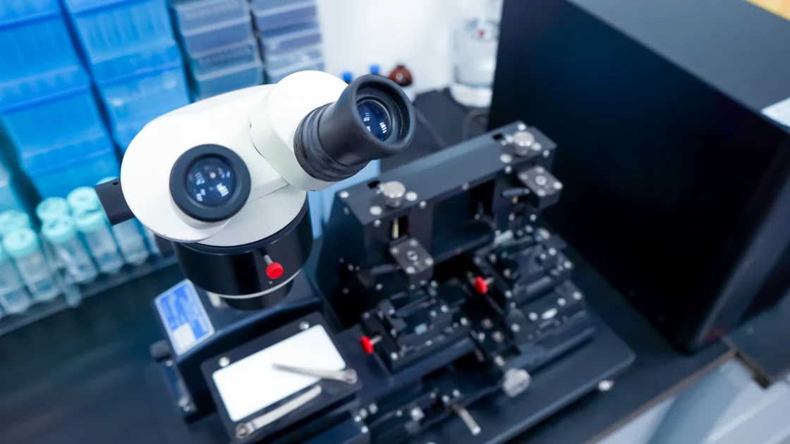 A laboratory microscope and precision instruments are set up for biosciences research, surrounded by sample tubes and equipment.