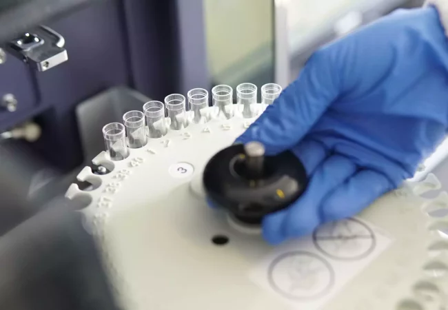 A gloved scientist adjusts a centrifuge filled with small test tubes, preparing samples for general toxicology analysis.