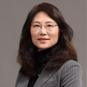 Connie Sun, Ph.D. - A professional woman with shoulder-length dark hair and glasses smiles softly. She is wearing a gray pinstripe blazer over a black top, perhaps ready to discuss radiolabelled ADME studies. The background is a plain, neutral gray.