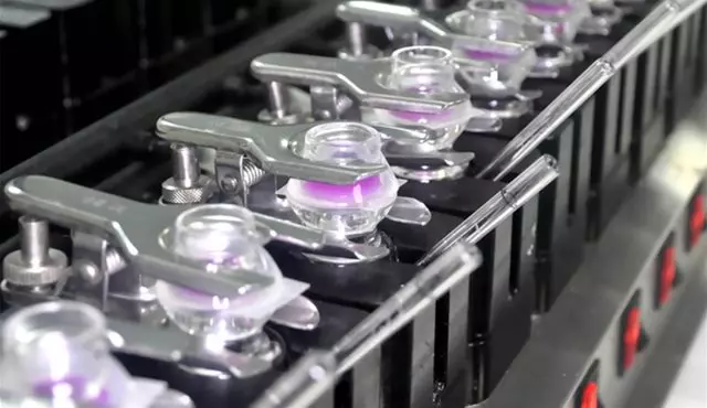 Glass diffusion cells with clamps secure samples, featuring purple membranes, in a row, used for dermal penetration studies in a controlled laboratory setting.