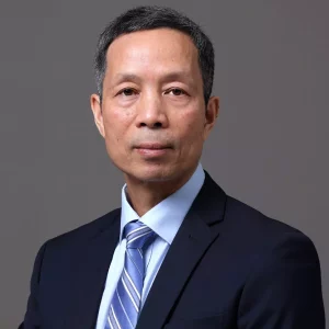 Dr. Hua Yang - A middle-aged man with short, salt-and-pepper hair is wearing a dark suit, light blue dress shirt, and a striped tie. He is posing against a simple gray background, looking directly at the camera with a neutral expression. The backdrop subtly nods to his expertise in preclinical ADME studies.