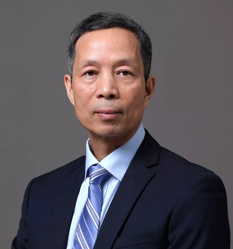 Dr. Hua Yang - A middle-aged man with short, salt-and-pepper hair is wearing a dark suit, light blue dress shirt, and a striped tie. He is posing against a simple gray background, looking directly at the camera with a neutral expression. The backdrop subtly nods to his expertise in preclinical ADME studies.