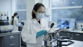 A scientist in protective gear operates equipment for tablet compression in a lab, focusing on formulation development processes.
