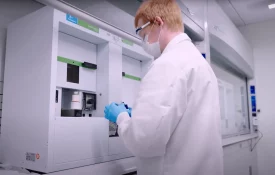 A scientist wearing protective gear works with advanced lab equipment to analyze radiolabelled compounds for human AME studies.