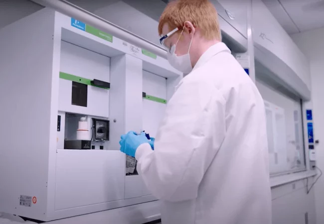 A scientist wearing protective gear works with advanced lab equipment to analyze radiolabelled compounds for human AME studies.