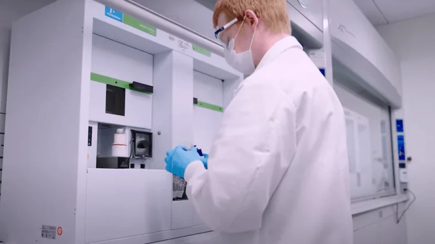 A scientist wearing protective gear works with advanced lab equipment to analyze radiolabelled compounds for human AME studies.