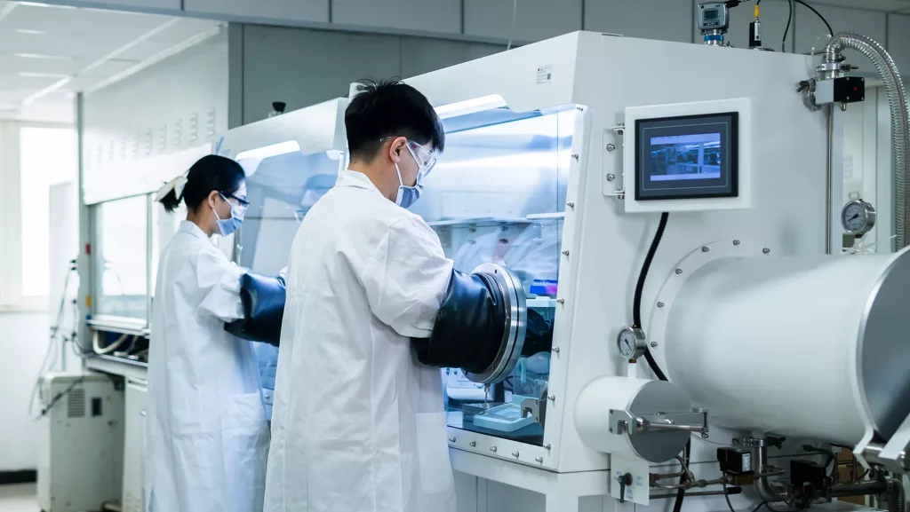 Two scientists in protective gear work with specialized equipment in a controlled laboratory setting, conducting advanced chemistry experiments.