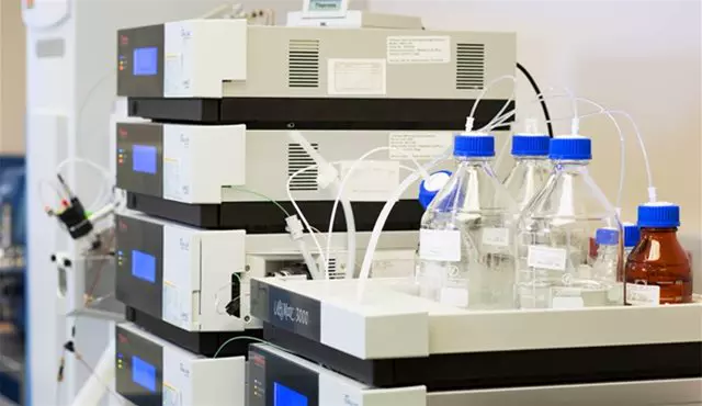 A high-performance liquid chromatography (HPLC) system with multiple stacked modules and connected solvent bottles, used for precise compound analysis.
