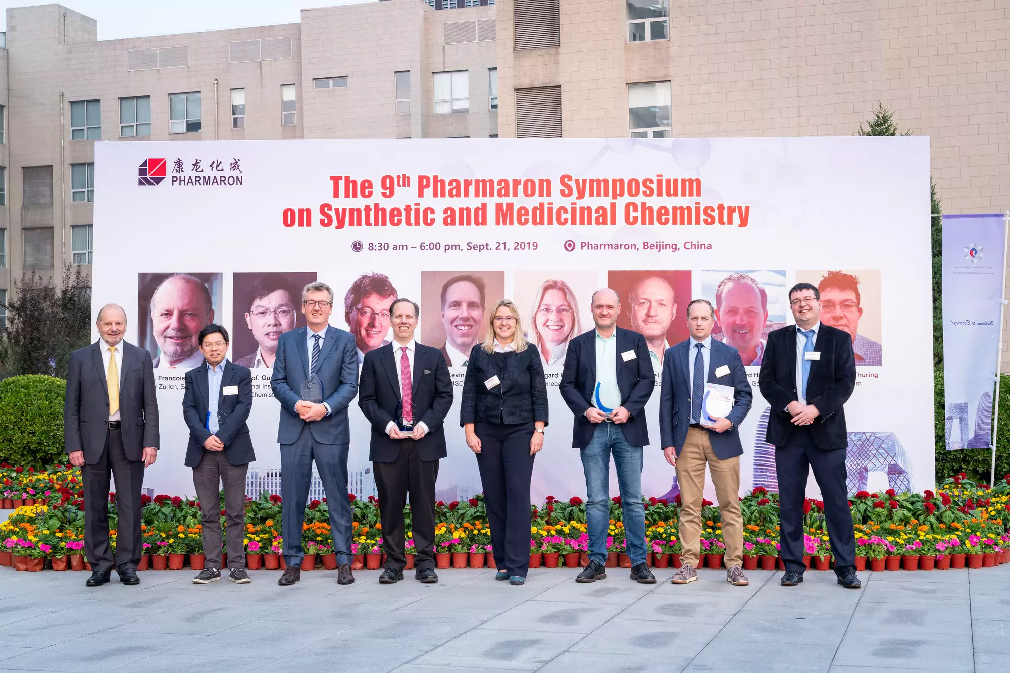Group of scientists posing in front of a banner at Pharmaron's 9th Symposium on Synthetic and Medicinal Chemistry held in Beijing, China, in 2019.