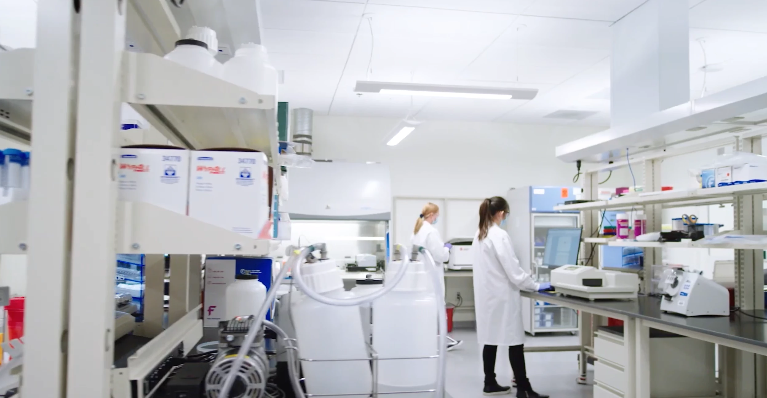 Scientists in lab coats and masks work in a spacious laboratory equipped with advanced instruments and supplies, highlighting integrated research services.