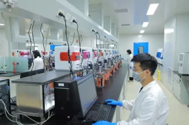 Scientists working in a process development lab, with multiple reactors and bioprocessing units connected to computers, analyzing and optimizing procedures.