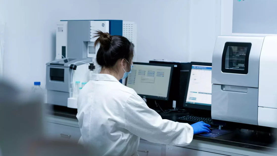 A scientist operates a Biacore system, analyzing molecular interactions on a computer in a biophysics lab setting.