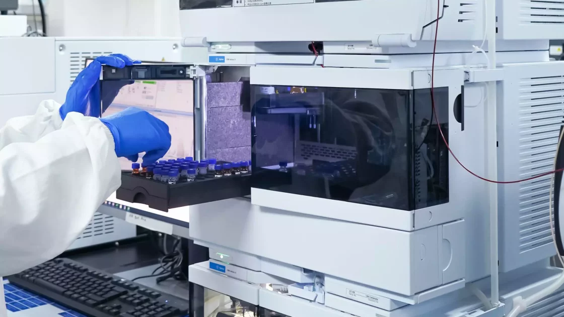 A scientist prepares vials in an HPLC machine for Carbon-14 bioanalysis, using advanced instrumentation for radiolabeled compound analysis.