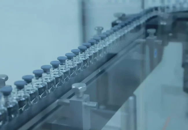 Rows of sealed vials move along an automated production line in a cGMP drug substance manufacturing facility, ensuring compliance and quality control.