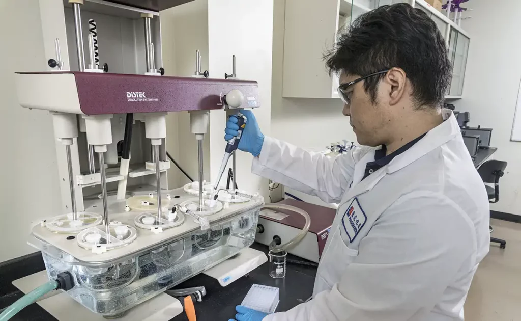 Scientist using a dissolution system to evaluate drug release, supporting BCS classification and potential biowaivers for oral formulations.