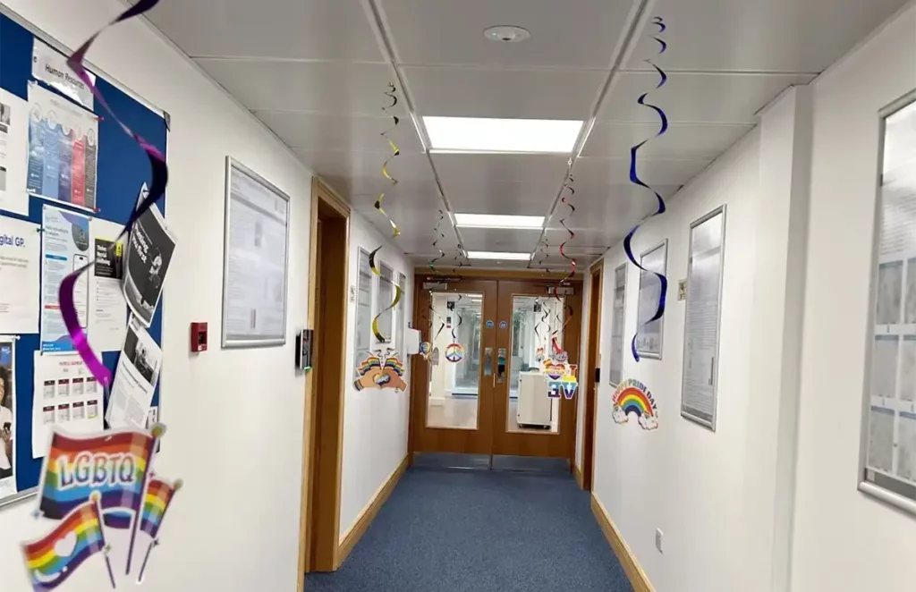 Office hallway decorated with rainbow streamers, LGBTQ+ signs, and Pride-themed posters for a Pride Month celebration.