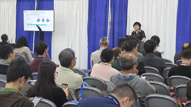 Scientist presents Pharmaron research to a seated audience at a conference, with a slide showing pie charts displayed on a screen.