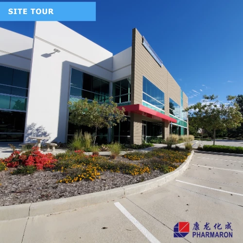 Pharmaron facility exterior on a sunny day, featuring modern architecture, landscaped grounds, and empty parking spaces during a site tour.