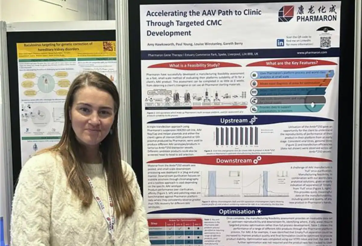 Scientist standing beside Pharmaron poster on accelerating AAV clinical development through targeted CMC strategies at the Advanced Therapies conference.