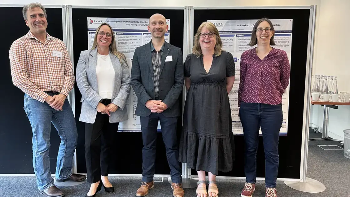 Group of scientists standing in front of research posters at a drug discovery event hosted by Pharmaron focused on ADME optimisation.