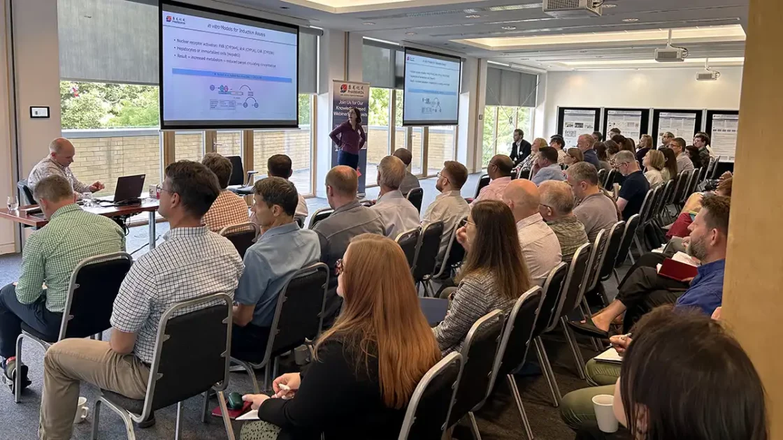 Audience listens to a scientific presentation on ADME optimisation at a Pharmaron-hosted drug discovery event with posters displayed in the background.